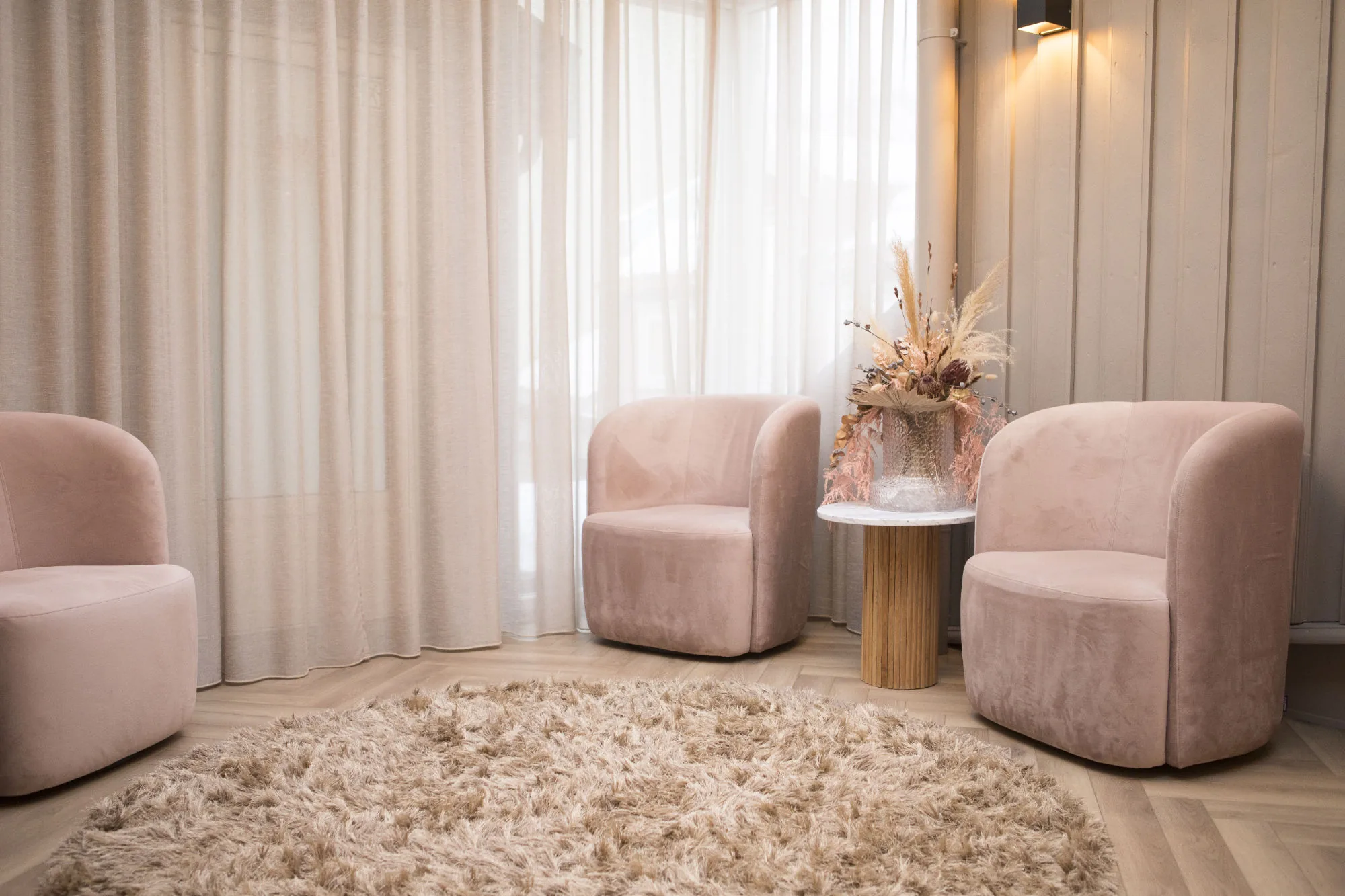 Loungen hos Injeksjonsspesialisten med rosa velourstoler og lyse gardiner